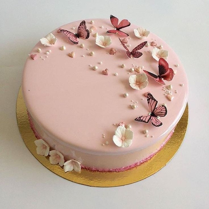 a pink cake decorated with butterflies and flowers