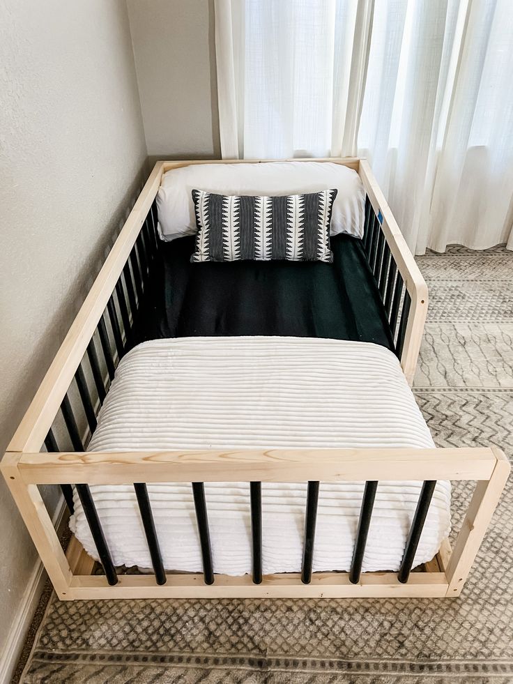 Black Montessori Floor Bed We want to make your toddlers transition from crib to bed easy and fun with our Sori Floor Beds! Our simple design keeps the safety of your child in mind and helps them feel safe and secure in a semi closed environment. Our beds will allow your child comfort and give them freedom of movement that can foster independence in their own space to help develop confidence. Our beds are not only great for your kiddos, but fantastic for those pre-bedtime snuggles with the famil Crib On Floor, Floor Crib Bed, Twin Floor Bed For Toddler, Montessori Boy Bedroom, Toddler Boy Bedroom Ideas Themes, Little Boy Room Ideas Toddlers, Neutral Toddler Boy Room, Toddler Boy Rooms, Montessori Crib