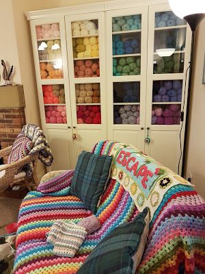 a living room filled with furniture and lots of crocheted blankets on top of it