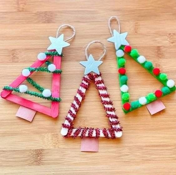 three christmas trees made out of popsicle sticks on a wooden surface with pom - poms