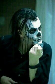 a man with white makeup and black hair wearing a skeleton mask