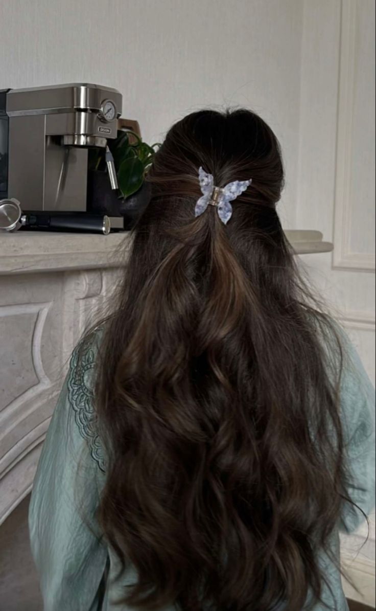 a woman with long hair sitting in front of a coffee maker