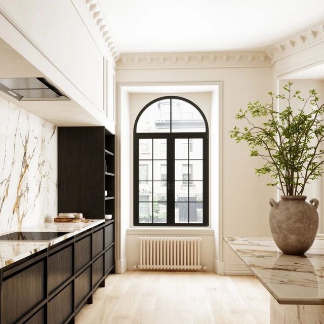 an elegant kitchen with marble counter tops and black cabinets, along with a potted plant