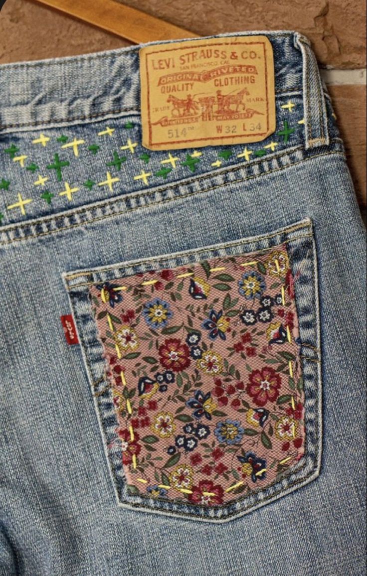 the back pocket of a pair of jeans with crosses and flowers on it, sitting on a wooden floor