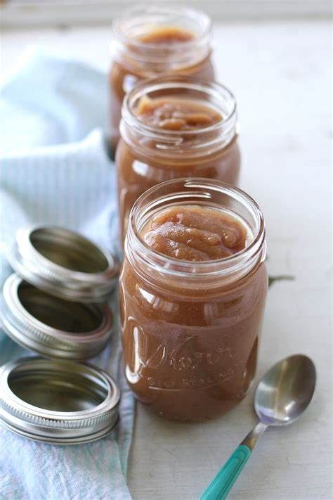 four jars filled with peanut butter sitting on top of a table next to spoons