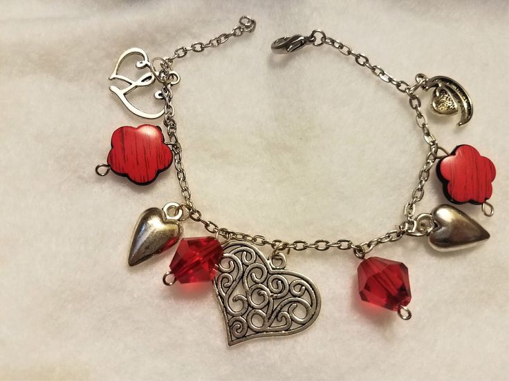 **PERCECT FOR VALENTINE GIFTING** This silver chained charm bracelet contains charms of silver with red companion beads closing with a lobster clasp. This piece is a finished length of approximately 8 inches long Handmade Metal Charm Bracelet For Valentine's Day, Red Dangle Bracelets As Gift, Handmade Silver Charm Bracelet For Valentine's Day, Red Charms For Valentine's Day Gift, Silver Charms Bracelets For Valentine's Day, Silver Bracelet With Dangling Charms For Valentine's Day, Red Charm Bracelet With Heart Charm As Gift, Handmade Red Charm Bracelet For Valentine's Day, Hypoallergenic Red Metal Jewelry