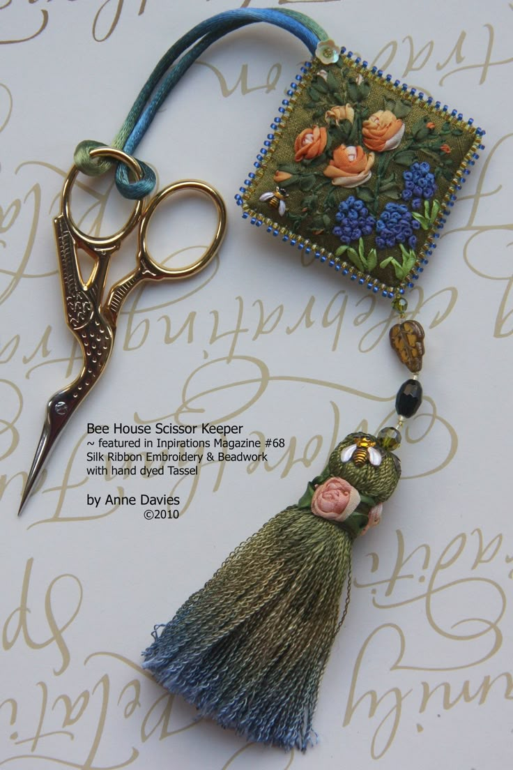 a pair of scissors and some fabric on a table with flowers, beads and thread