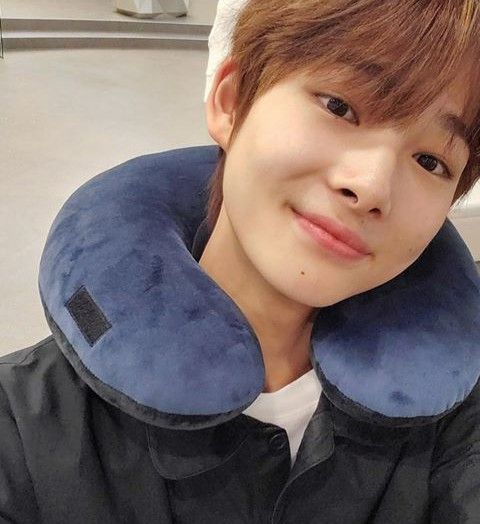 a young man wearing a blue neck pillow