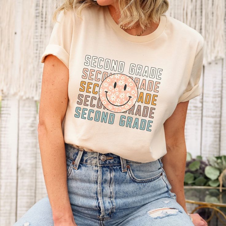 a woman wearing a t - shirt that says first grade first grade with a smiley face on it