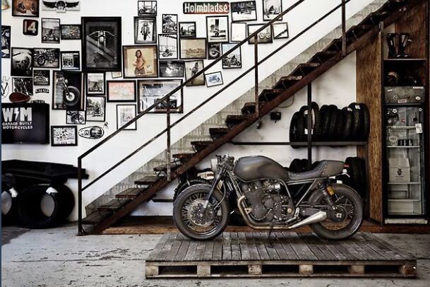 a motorcycle parked in front of a stair case with pictures on the wall behind it