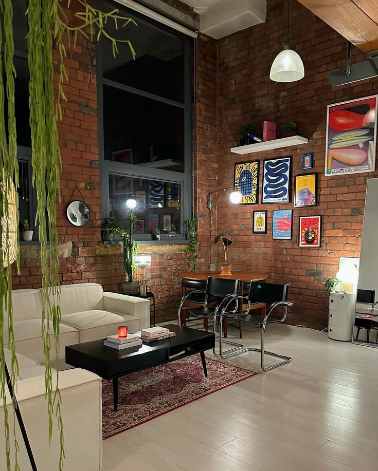 a living room filled with furniture next to a brick wall covered in pictures and plants