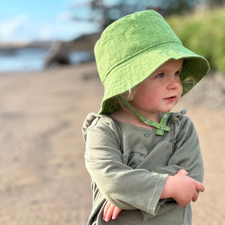 "This baby and toddler summer bucket hat is the perfect thing for sunny summer days!  Washable linen and cotton fabric makes it an easy go to for at the park, the beach, or even the backyard!  This hat will protect delicate skin from the sun and will quickly become a favorite accessory! See link below for Mommy version. I made this sun hat from a grass green colored linen/cotton blend fabric to go with every outfit.  The strap closes with snaps under the chin keeps them from pulling it off.  Bri Summer Hats With Uv Protection For Playtime, Summer Sun Hat With Upf 50+ For Playtime, Cute Cotton Hat For Outdoor, Cute Cotton Outdoor Hat, Playful Handmade Sun Hat For Summer, Summer Playtime Hat With Curved Brim, Adjustable Summer Bucket Hat For Playtime, Playful Wide Brim Sun Hat For Playtime, Summer Play Brimmed Bucket Hat