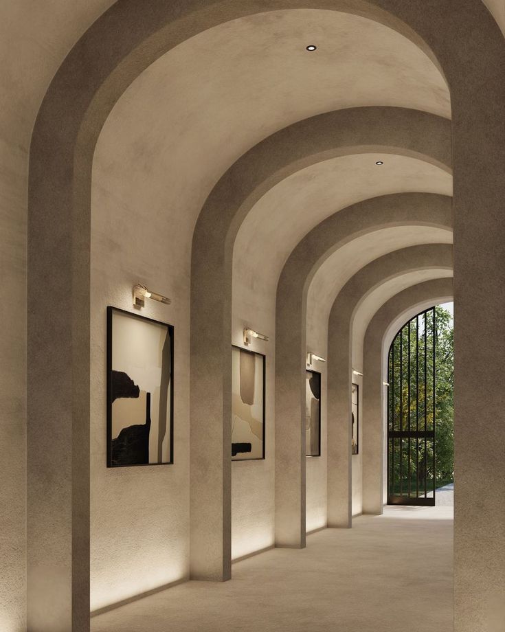 an empty hallway with arches and paintings on the wall, along with lights from lampshades