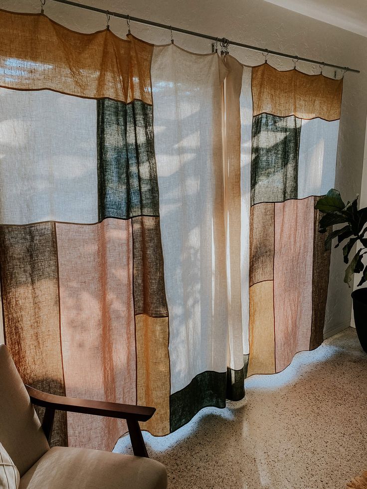 a living room with a couch, chair and window covered in sheer curtain panels that have multicolored squares on them