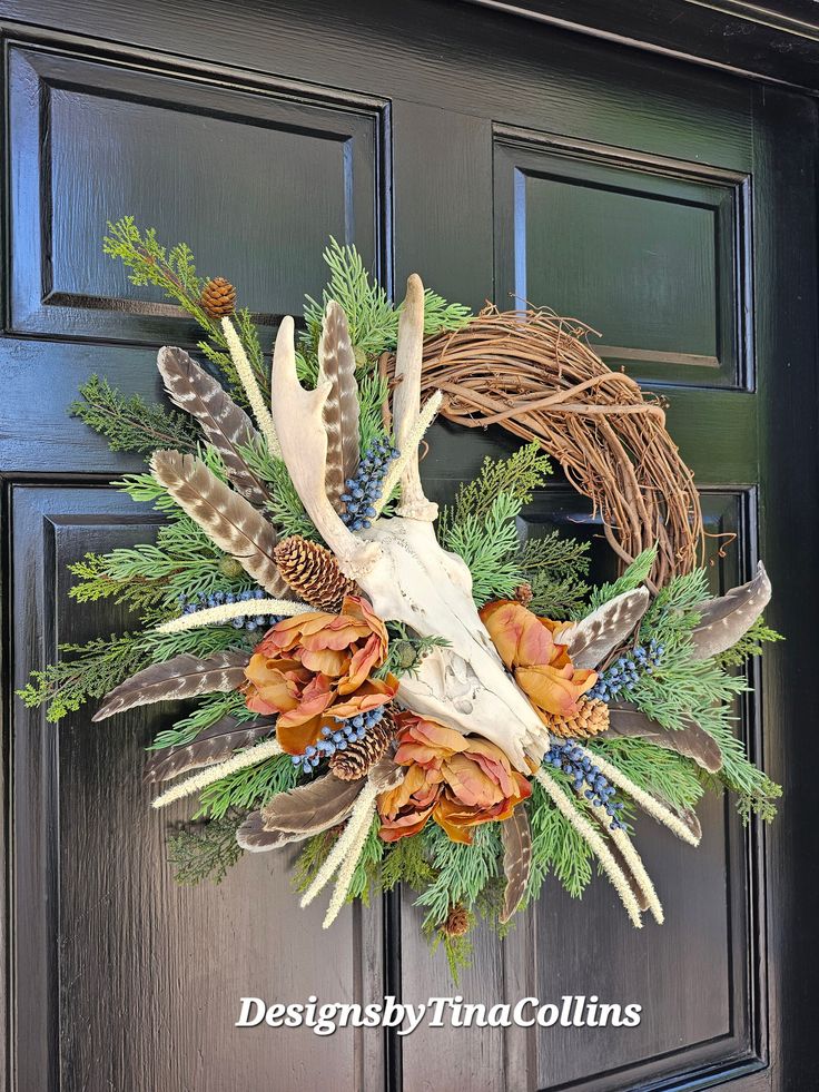 a wreath with antlers, feathers and flowers is hanging on the front door doors