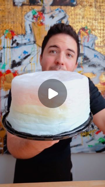 a man holding a cake with white frosting on it