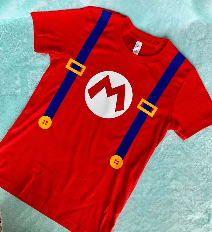 a red t - shirt with the letter m on it is laying on a blue blanket