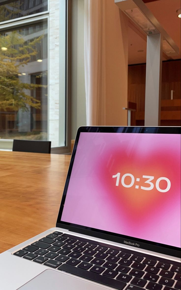 an open laptop computer sitting on top of a wooden table in front of a window