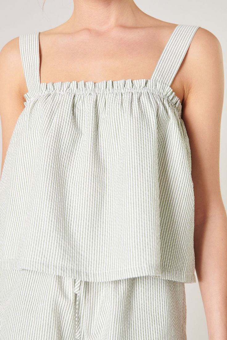 The perfect closet refresher has arrived. Beat the heat in this simply refined seersucker crop top with a ruffle trim elastic top edge. It maintains a relaxed A line fit creating a balanced shape. Pair it with the matching Taliya Seersucker Drawstring Shorts for the ultimate matching set.- Seersucker stripe- Elastic top edge- Sleeveless- A line- Color: Green WhiteSize + Fit - Model is 5'9" and wearing size XS- Measurements taken from size S - Chest: 33"- Length: 13 1/2" Fabric Self: 100% CottonL Striped Seersucker Tops For Spring, Spring Striped Seersucker Tops, Spring Seersucker Tops, Striped Seersucker Tops For Summer, Casual Ruffle Hem Crop Top For Spring, Casual Spring Crop Top With Ruffle Hem, Summer Striped Tops With Ruffles, Perfect Closet, Elastic Top