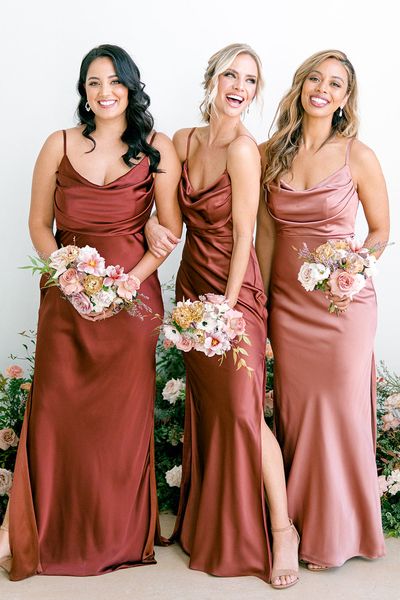 three women in long dresses standing next to each other with bouquets on their laps