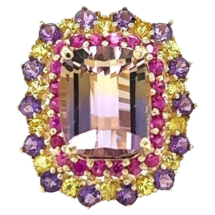 Ametrine, Pink and Yellow Sapphire 7.88 Carat Yellow Gold Cocktail Ring This ring definitely has a WOW factor! Flashing a vivid color of yellow and purple the vibrant Emerald Cut Ametrine sits between Yellow and Pink Sapphires and Diamond accents. Item Specs: Ametrine (Emerald cut stone) = 5.64 carats 14 Amethysts (Round Cut) = 0.86 carats 38 Yellow and Pink Sapphires (Round Cut) = 1.38 carats Total Carat Weight of the Ring = 7.88 carats 14KY Gold = 7.8 grams Ring size is 7 and can be re-sized at no additional cost Fun Facts about Ametrines: The ametrine stone is golden yellow and purple, something that happens when citrine and amethyst stones come into contact to form one crystal. This also gives the stone its name, derived from AMEthyst and ciTRINE. It is also referred to as bolivianite, Yellow Gold Cocktail Ring, Amethyst Stones, Deco Luminaire, Bracelet Love, Yellow And Purple, Gold Cocktail Ring, Gold Cocktail, Orange Sapphire, Yellow And Pink