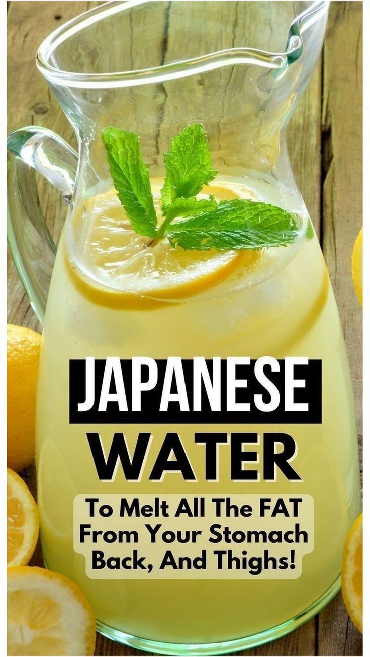 a pitcher filled with lemonade next to sliced lemons and mint on a wooden table