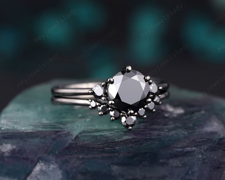 a black diamond ring sitting on top of a rock