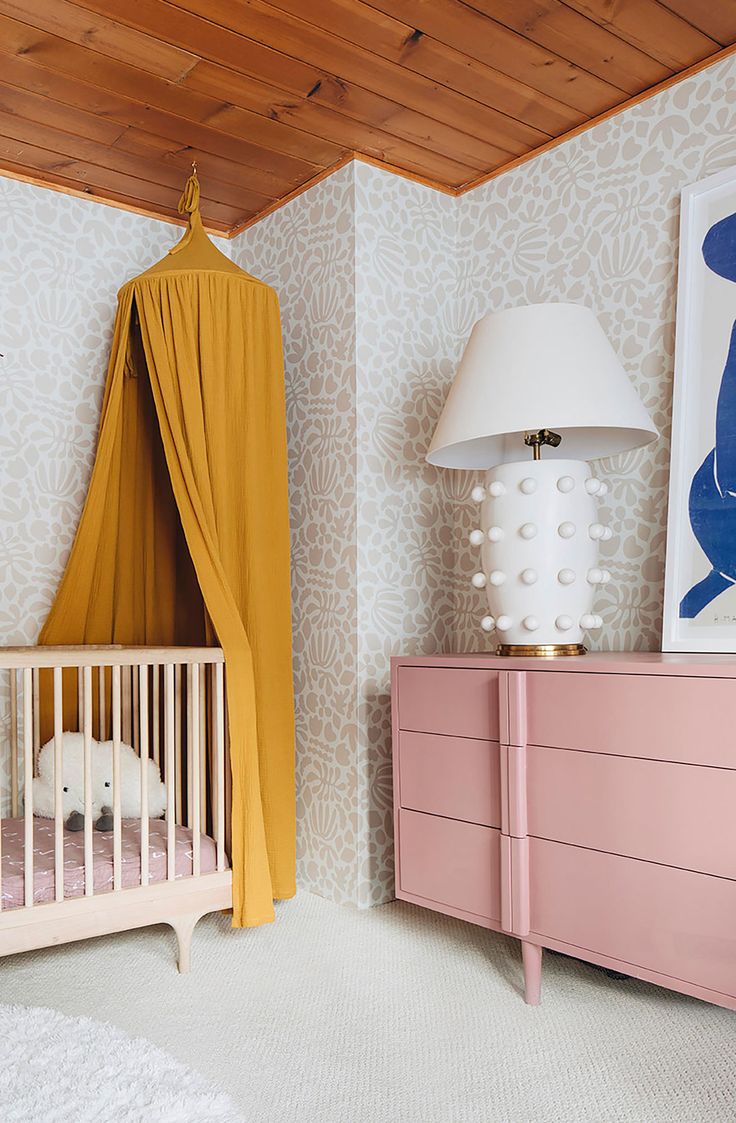 a baby's room with a pink dresser and yellow canopy