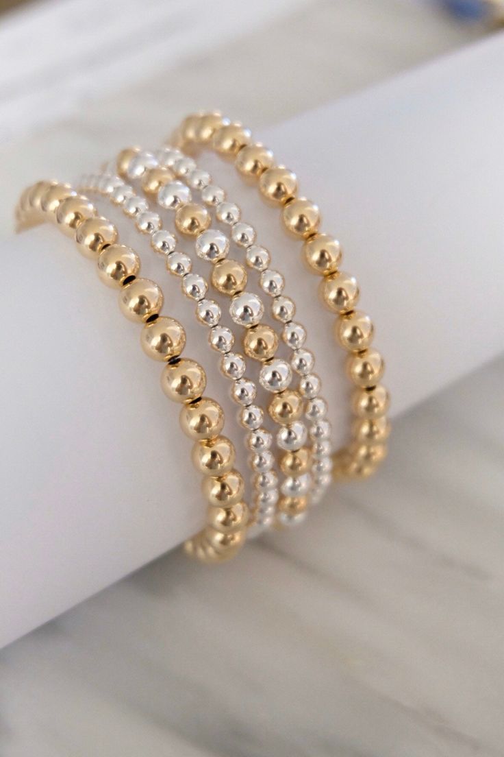 Set of 5 beautiful gold-filled and sterling silver stretchy bracelets. It has a nice two-tone color and look so pretty when they are worn. This is a great value if you want to jumpstart your collection! - 2 sterling silver bracelets with 3mm beads - 2 gold-filled bracelets with 6mm beads - 1 mix of gold-filled and sterling silver with 5mm beads Made of high quality gold-filled and sterling silver beads, strung on a stretchy cord. Made in Los Angeles CA Silver And Gold Beaded Bracelet, Rose Gold Beaded Bracelet, Diy Earrings Materials, Homemade Bracelets, Silver Beaded Bracelet, Gold And Silver Bracelets, Sterling Silver Bead Bracelet, Black Beaded Bracelets, Silver Bead Bracelet