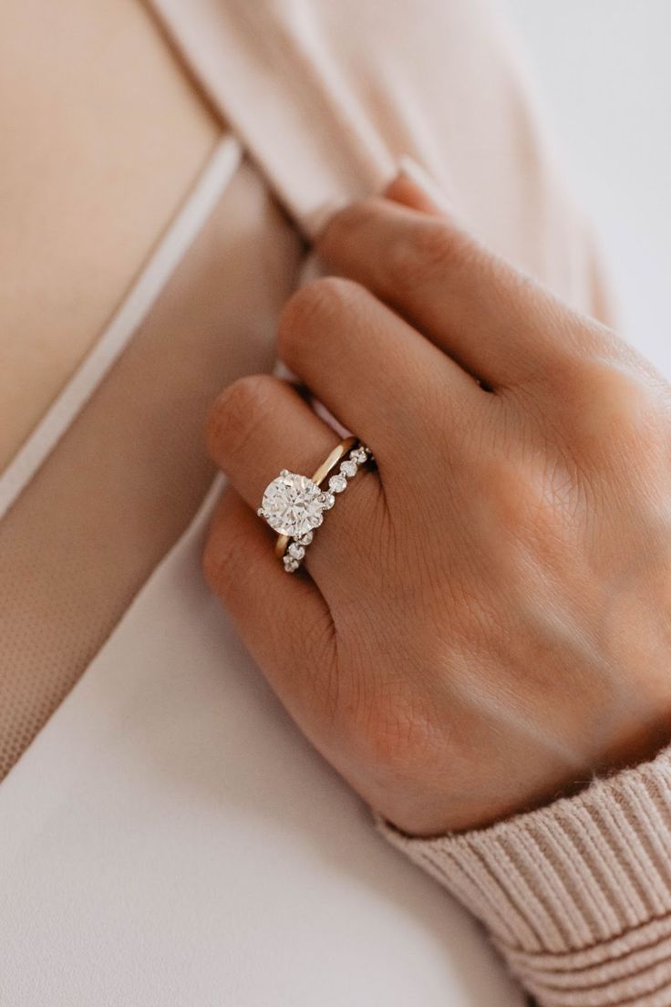 a woman's hand with a diamond ring on her left wrist, wearing a beige sweater