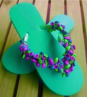 a pair of green flip flops with purple flowers on the bottom and blue straps