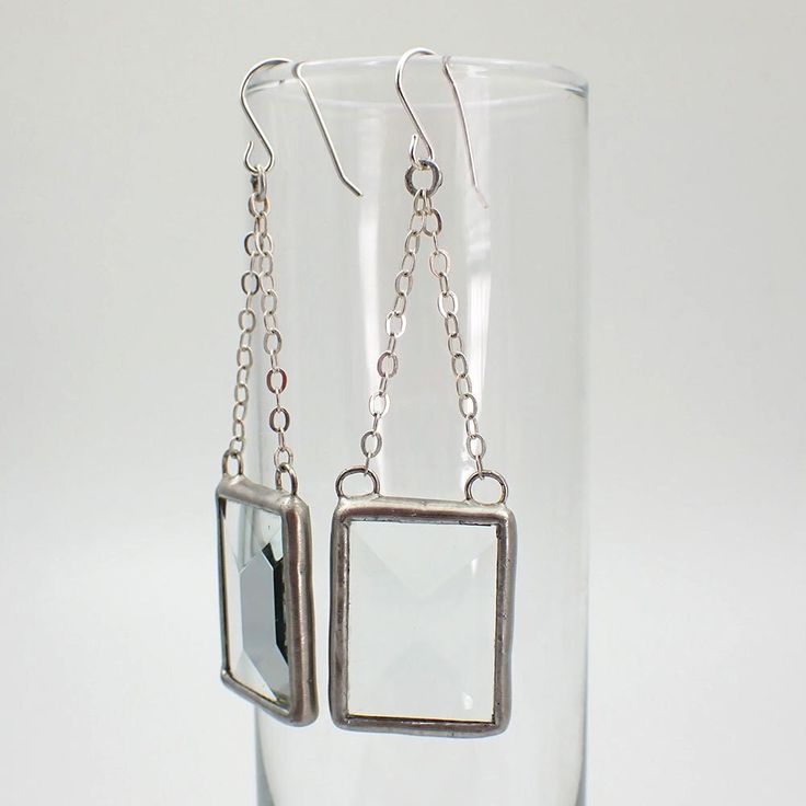 "Clear, rectangular stained glass bevel earring pair edged in silver, attached to sterling silver cable chain. The simple french hook ear wires are sterling silver.  Total Size: 3\" x 1\" each Each item by Faerie Glass is 100% uniquely hand-crafted with quality materials that are lead-free. NOTE - All photographs are taken in effort to best represent the product. Color of actual jewelry may vary slightly from photographs." Modern Silver Earrings With Rectangular Pendant, Modern Silver Rectangular Pendant Earrings, Silver Jewelry With Rectangular Pendant And Matching Earrings, Silver Jewelry Set With Rectangular Pendant And Matching Earrings, Everyday Silver Glass Jewelry, Elegant Silver Glass Earrings, Silver Glass Jewelry With Ear Wire, Modern Rectangular Glass Jewelry, Stained Glass Earrings