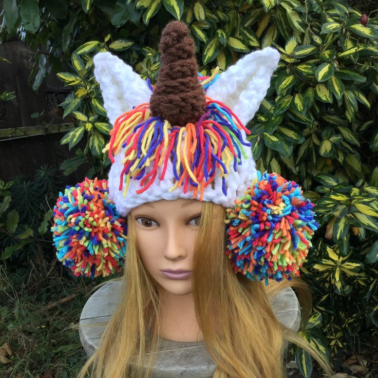 a wig wearing a hat with multicolored pom poms on it's head