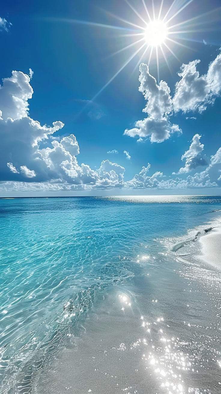 the sun shines brightly over an ocean beach with clear blue water and white clouds