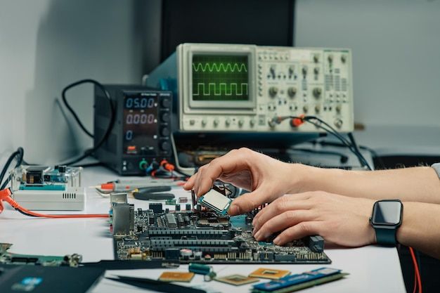 a person working on a circuit board in front of some other electronic devices and equipment