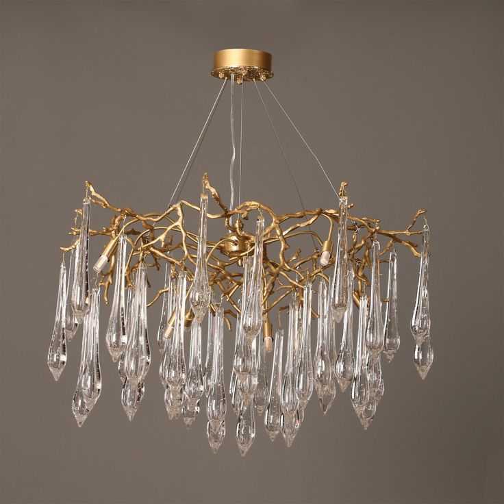 a gold chandelier with crystal drops hanging from it's center and leaves on the bottom