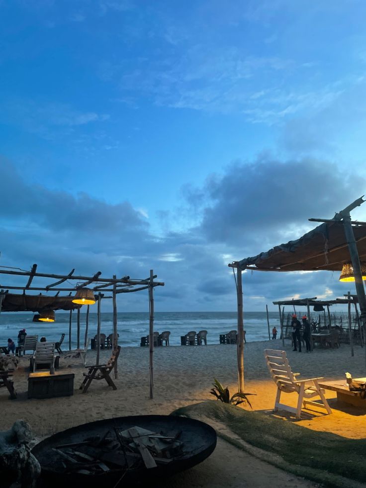 an outdoor dining area on the beach at dusk