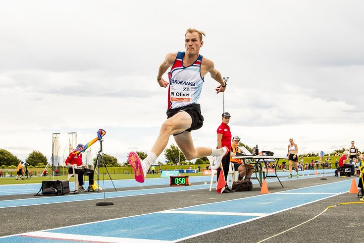 a man running on a track with other people watching