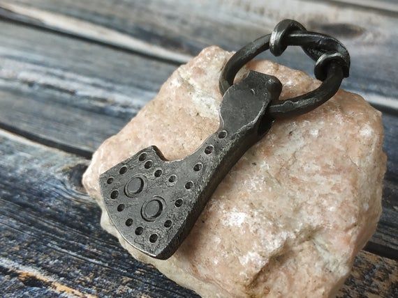 a piece of metal sitting on top of a rock next to a black chain with holes in it