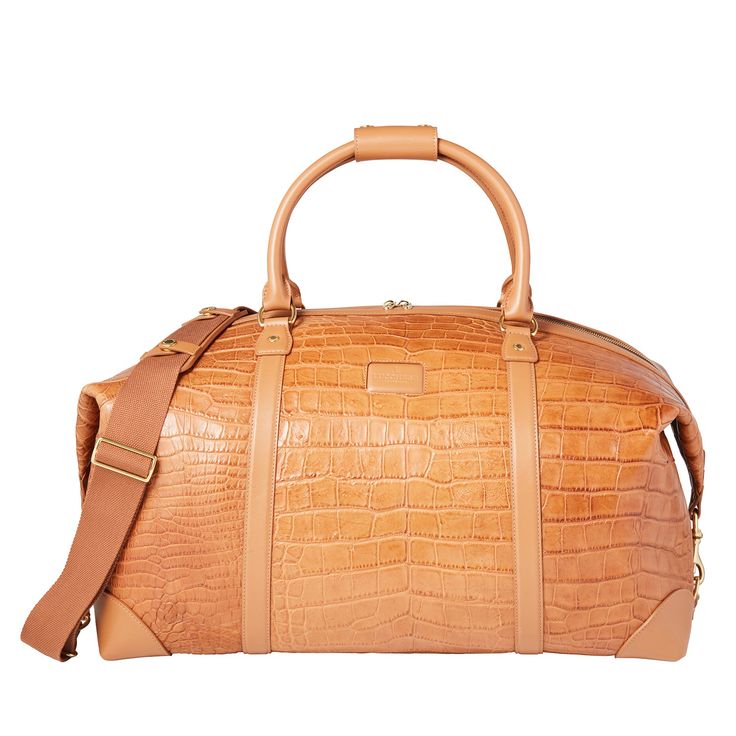 Built with Lucchese's own giant American alligator, this signature duffle totes your essentials in first class style. The fold-end construction allows for maximum packing space, which includes natural, water-resistant canvas lining, an interior zipper pocket and two open storage slots. Classic Travel Bag With Crocodile Pattern, Luxury Brown Luggage With Large Capacity, Luxury Large Capacity Brown Luggage, Luxury Rectangular Luggage With Leather Lining, Luxury Brown Duffle Bag With Large Capacity, Luxury Cognac Weekender Bag With Leather Handles, Luxury Large Capacity Brown Duffle Bag, Luxury Brown Luggage With Leather Handles, Luxury Cognac Travel Bag For Business Trips