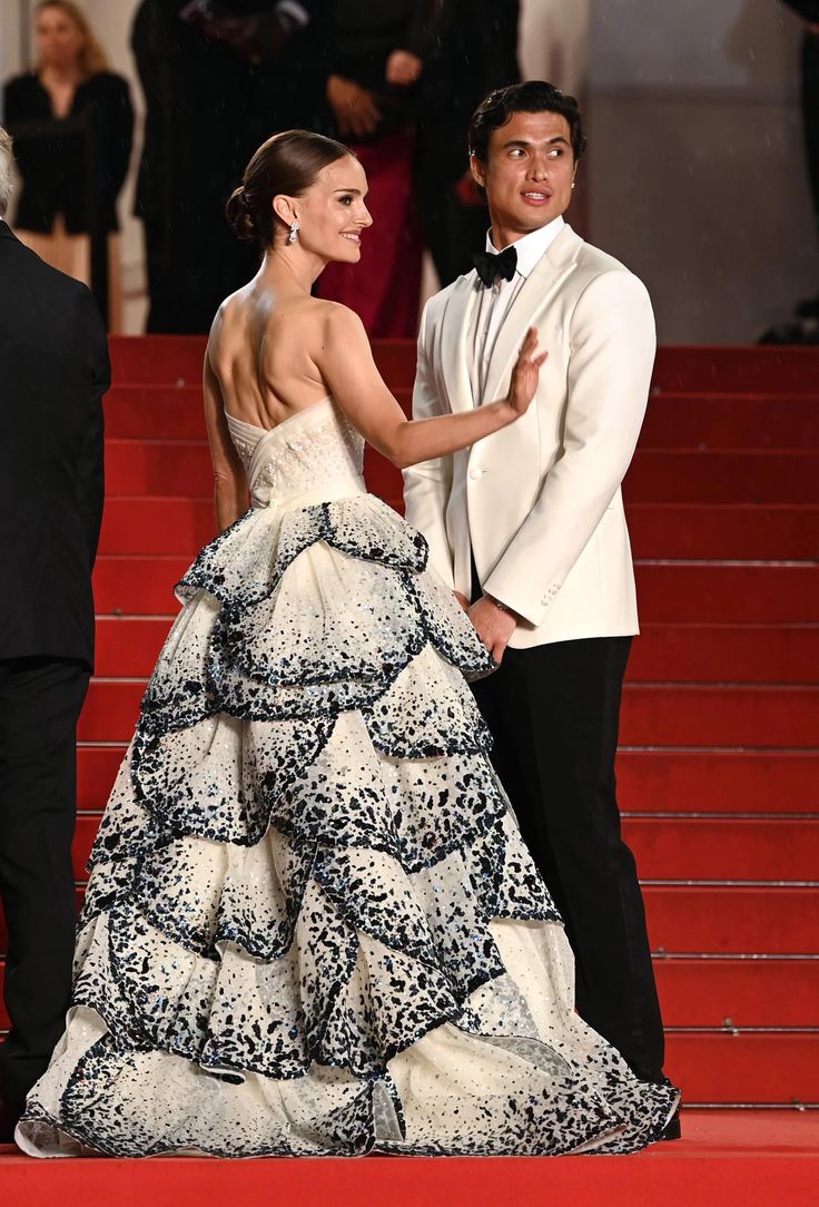 a man and woman in formal wear standing on the red carpet with their arms around each other