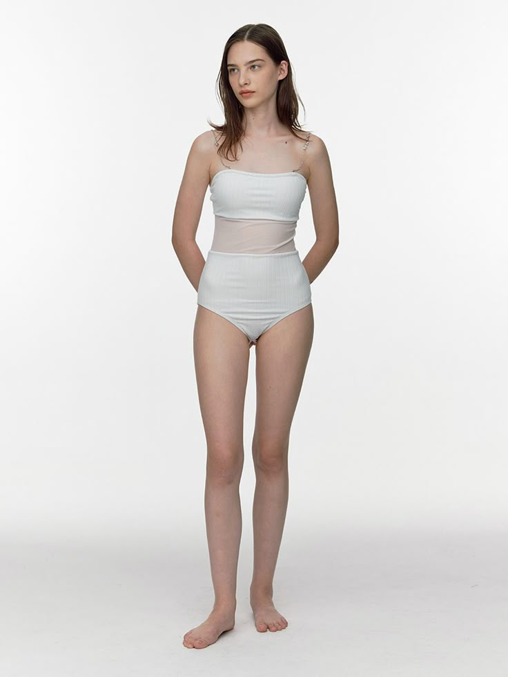 a woman in a white bodysuit is posing for the camera with her hands on her hips