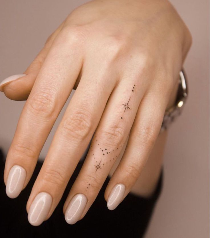 a woman's hand with a small star tattoo on her left thumb and finger