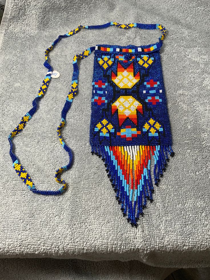 a colorful beaded purse sitting on top of a white towel next to a blue bag