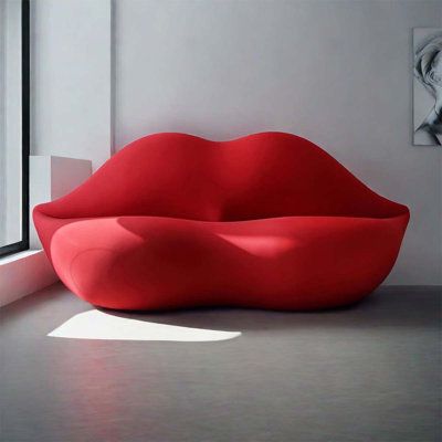 a red couch sitting in front of a window next to a painting on the wall