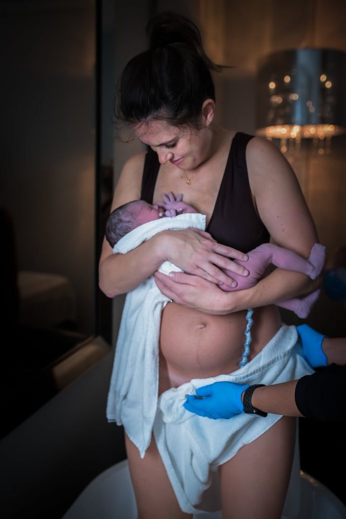 a woman holding a baby wrapped in a towel while wearing blue gloves and rubber gloves