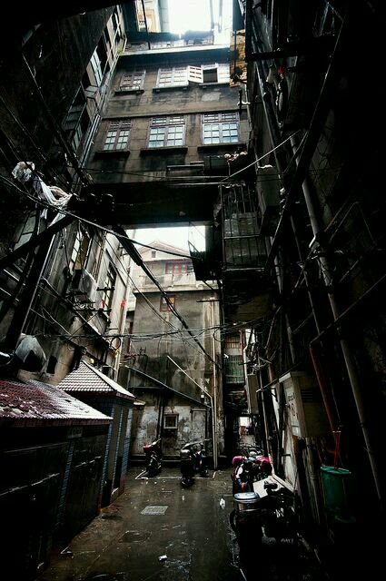 an alley way with scaffolding and parked cars