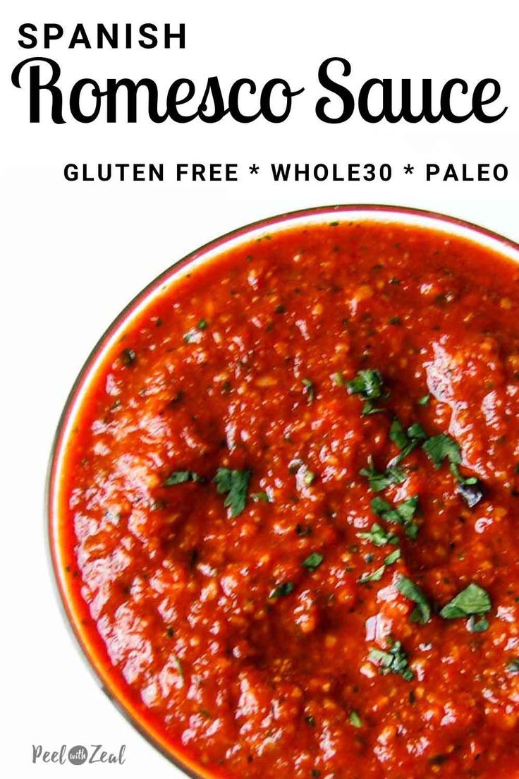 a bowl filled with tomato sauce on top of a white table