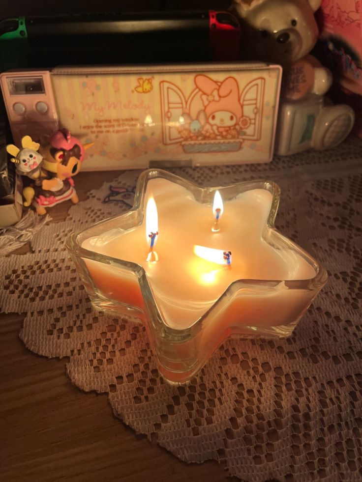 two lit candles sitting on top of a doily next to a teddy bear and other toys