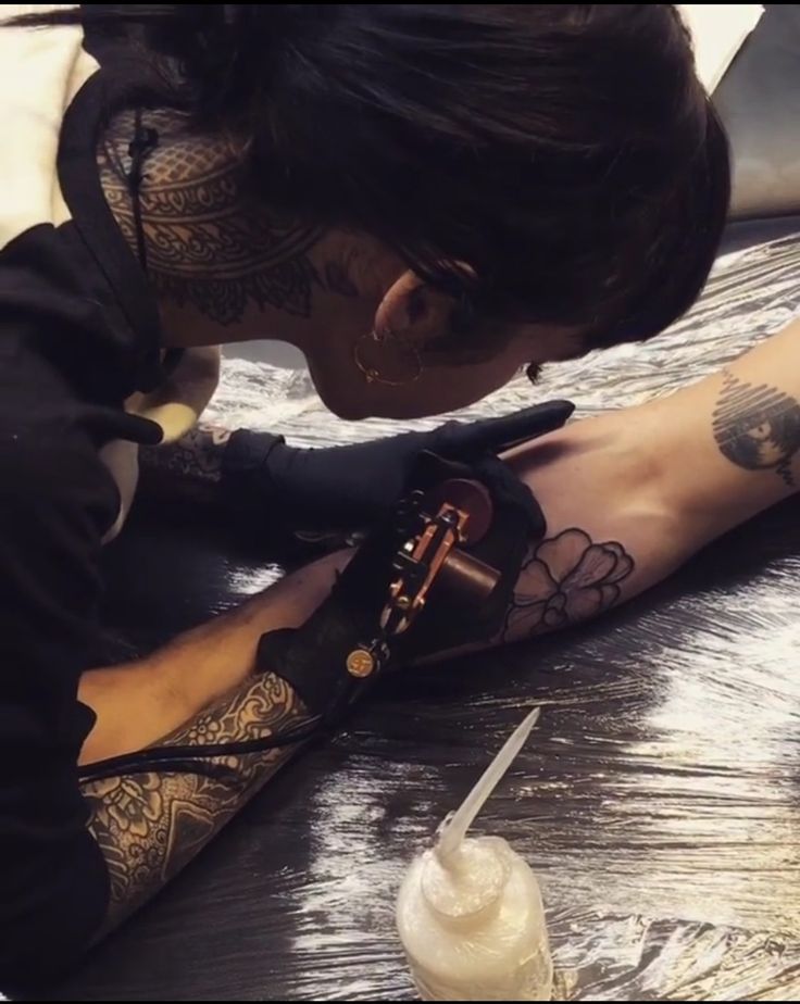 a woman with tattoos on her arm and leg is getting ink done by someone else